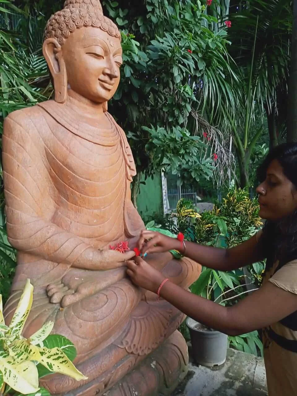 Pic of girls tying the holy thread to Buddha Statue